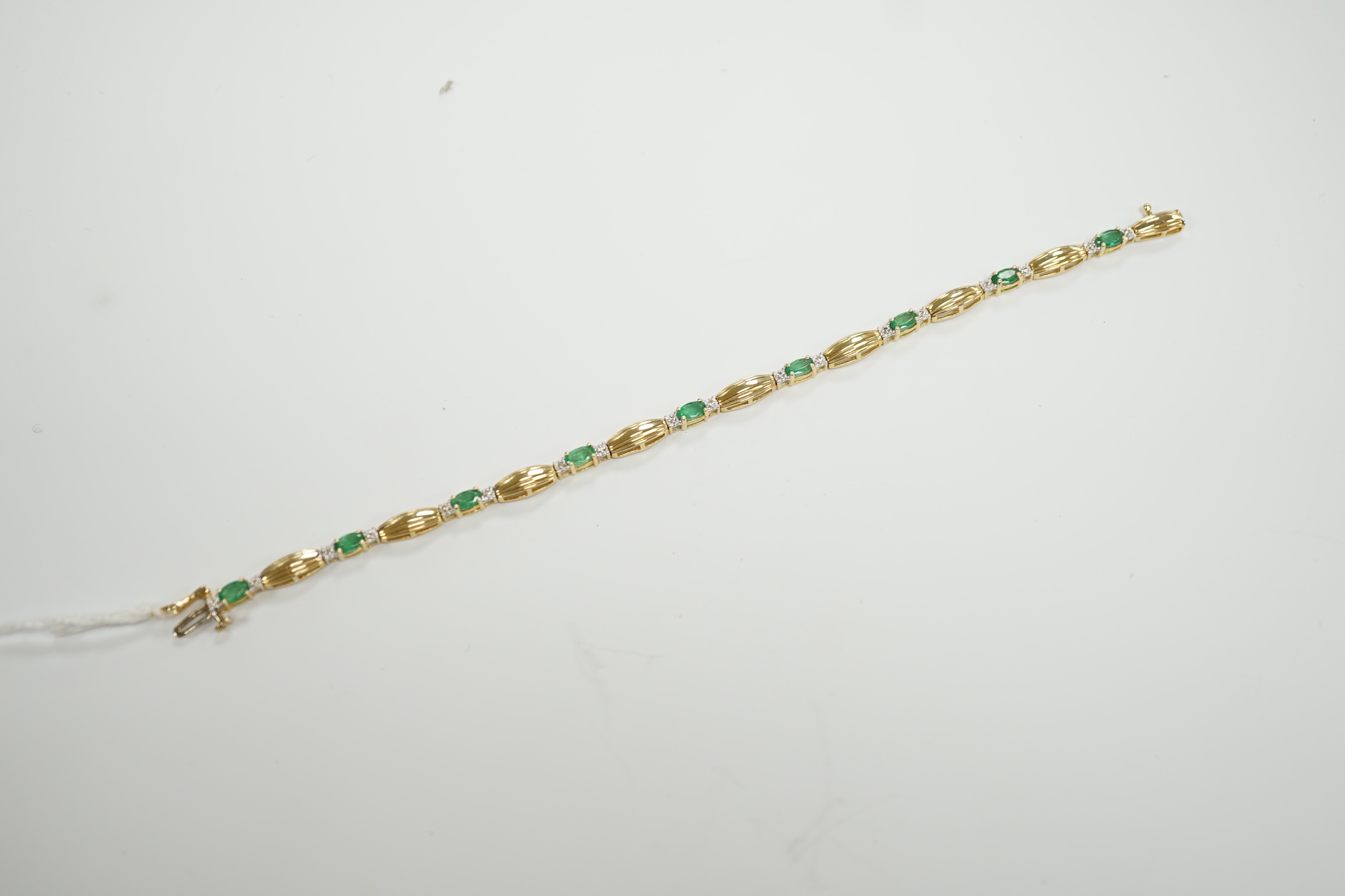 A modern yellow metal, emerald and diamond chip cluster set bracelet, 17.7cm, gross weight 7.6 grams.